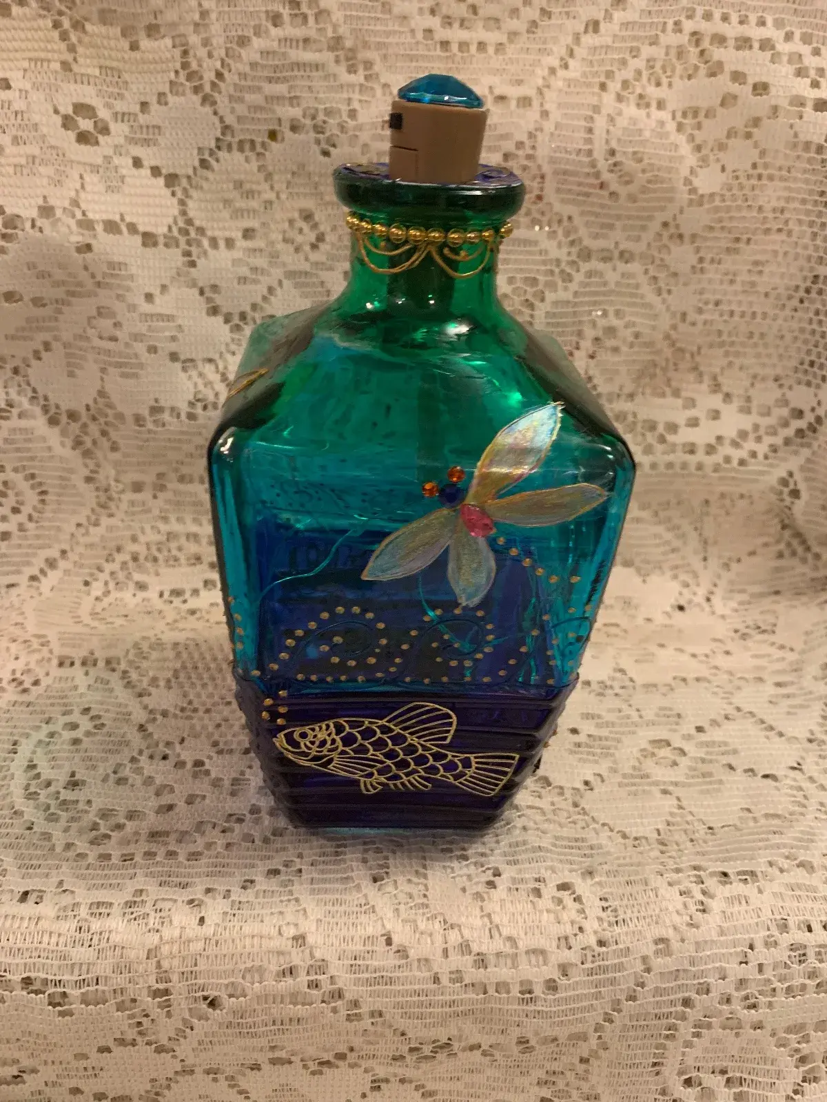 Unique shaped bottle. Hand painted dragonfly in colours of bright green, turquoise and cobalt blue. Enhanced with fairy lights .