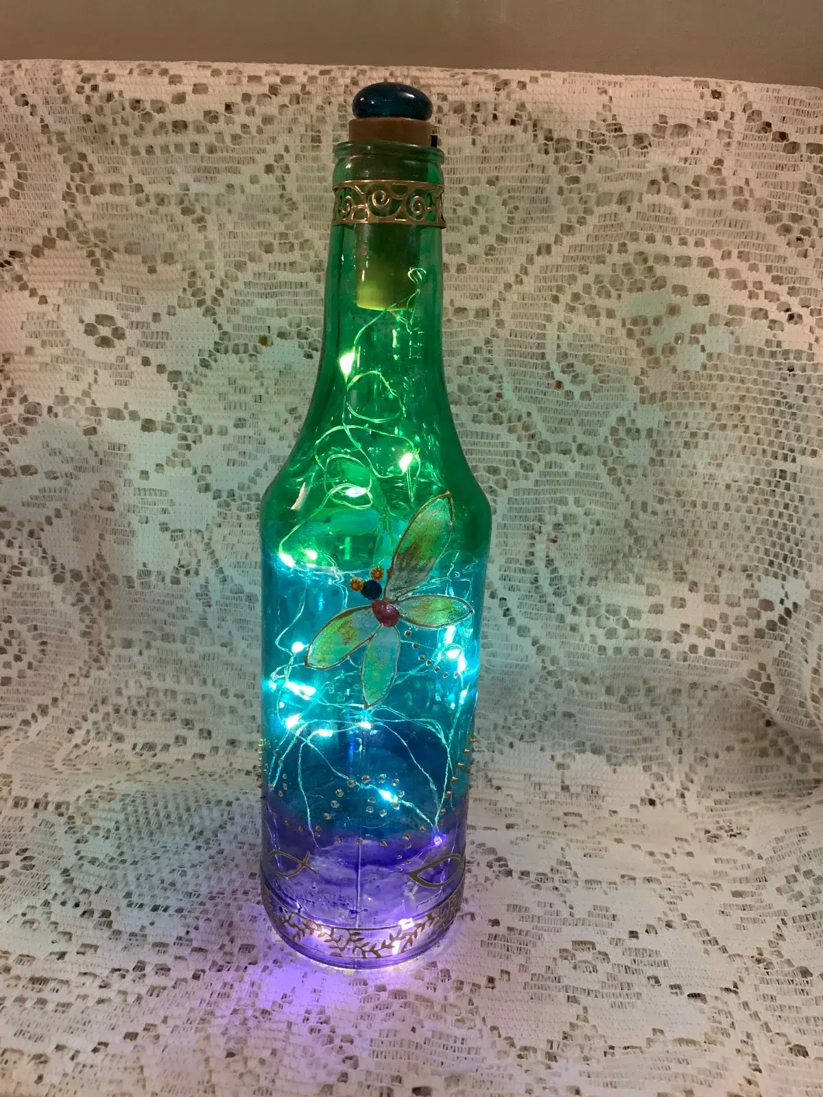 12 inch dragonfly bottle. Hand painted using glass paints in turquoise, green and royal blue.with fairy lights. Fairy lights use 3 button batteries.